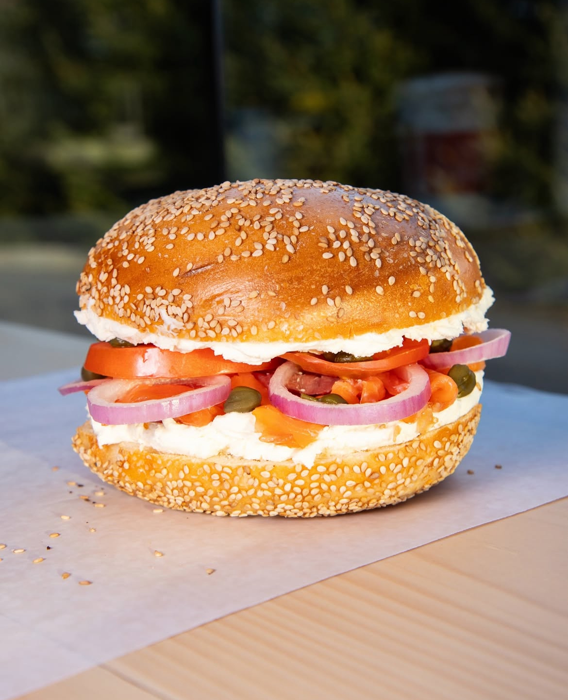 Sesame bagel with lox, cream cheese, tomatoes, and capers